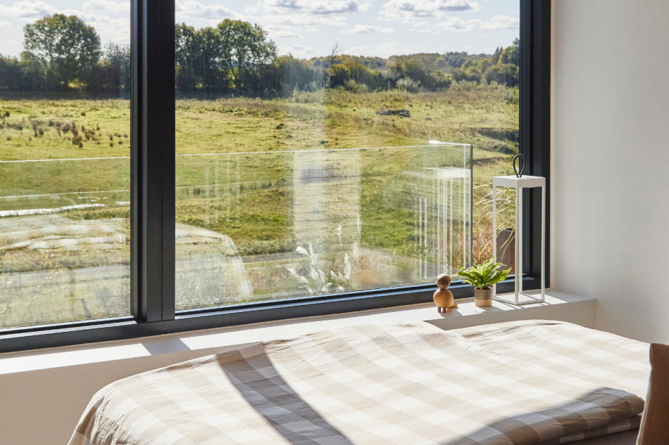Soveværelse med stort vinduesparti og udsigt over landskab
